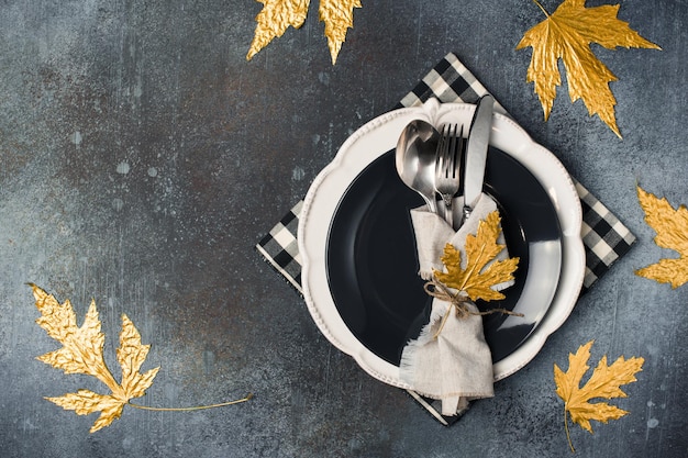 Autumn thansgiving and halloween tableware flat lay with plate and leaves and dark background copy spacetop view