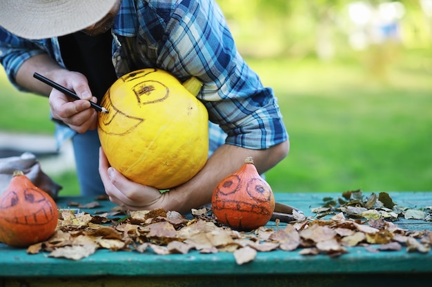 秋の伝統と休日のハロウィーンの準備。自然の中の家、カボチャで作られたランプがテーブルで切り取られています。