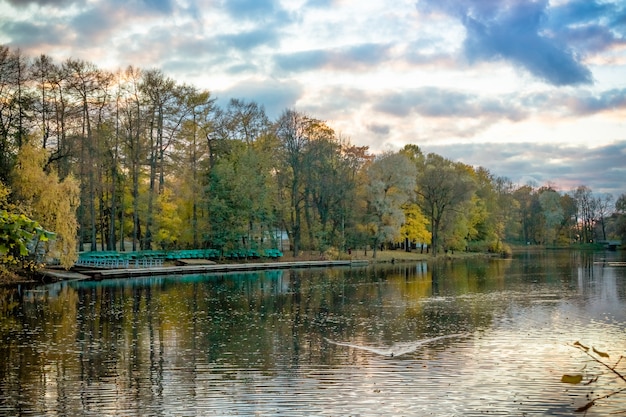 Autumn trees reflected in water. Colorful autumn morning in the city park with boat station. Colourful autumn lake. Colorful landscape. Happy fall season