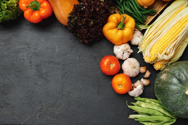 Autumn vegetable composition with pumpkin, corn and pepper on black background