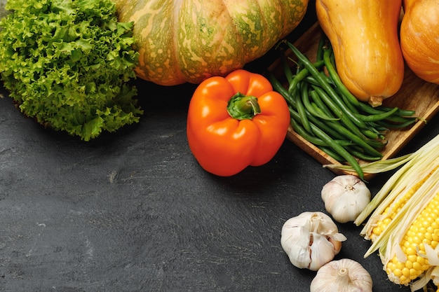 黒の背景にカボチャ、トウモロコシ、コショウと秋の野菜の組成物