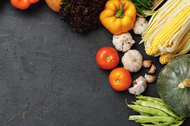 Autumn vegetable composition with pumpkin, corn and pepper on black background