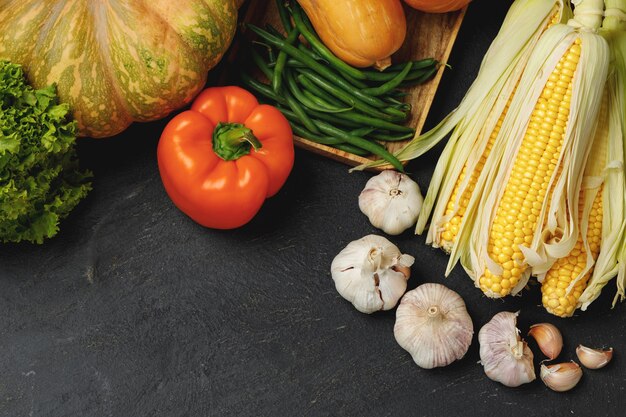 Autumn vegetable composition with pumpkin, corn and pepper on black