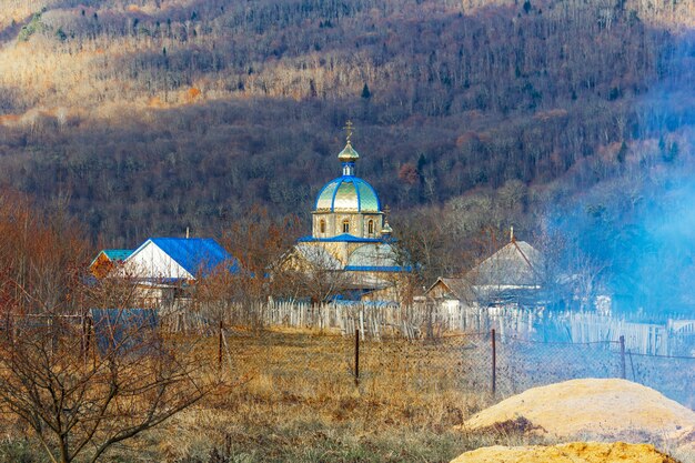 Autumn village landscape with an Orthodox Church on a forest