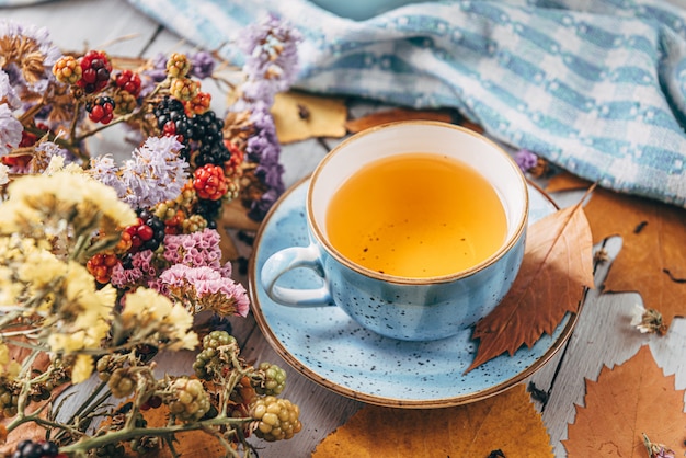 Autumn warming tea on a wooden table with autumn tree leaves lying nearby