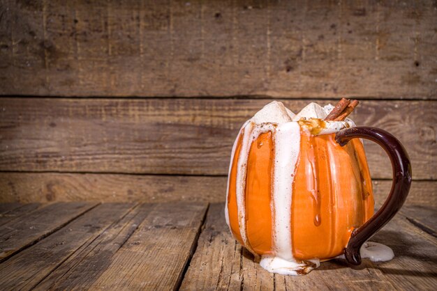 Autumn, winter drink for Christmas, Thanksgiving, Halloween. Funny cup of spicy pumpkin latte, hot chocolate, with whipped cream, marshmallow, spices with book, warm plaid and decoration