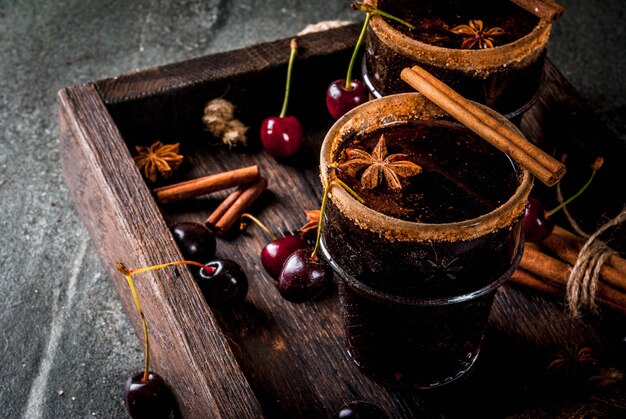 Autumn and winter drinks. Hot cherry  sangria with cinnamon, anise, wine and spices. On a stone dark and wooden  with ingredients, , in tray