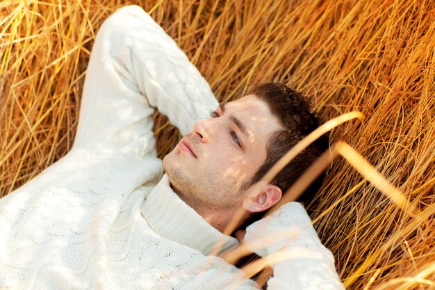 Autumn winter man portrait laying in golden grass