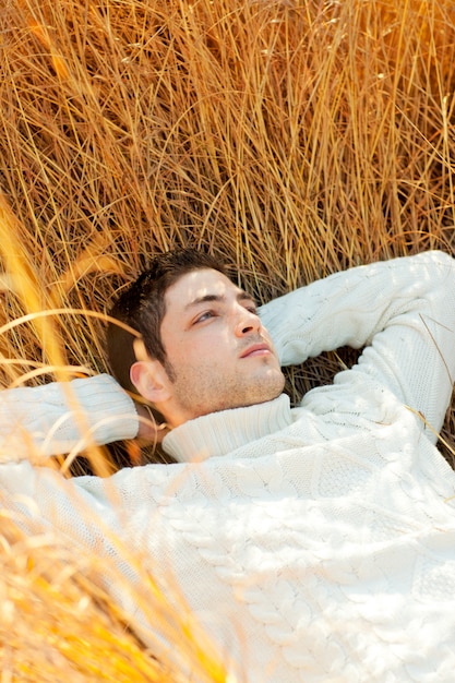 Autumn winter man portrait laying in golden grass