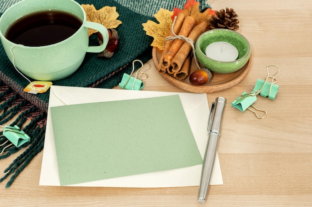 Autumn or winter season cozy composition with greeting card tea cup pen on desk table