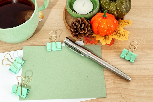 Autumn or winter season cozy composition with greeting card tea cup pen on desk table