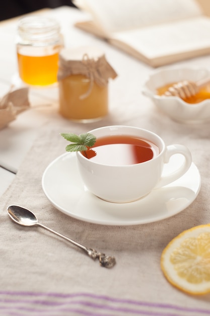 Tazza di tè e libro di natura morta di autunno o di inverno sul tavolo