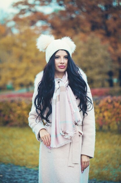 Autumn woman brunette wearing coat hat and scarf outdoors Beautiful girl in fall park