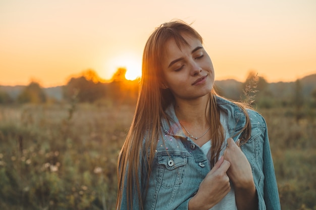 Foto donna di autunno che gode della natura sul campo. donna di bellezza all'aperto che solleva le mani ai raggi del sole. bellissima modella adolescente donna in abito bianco in esecuzione sul campo, luce solare. glow sun. donna felice libera