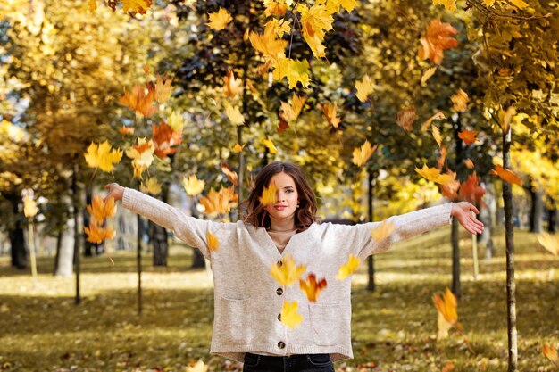 Осенняя фотомодель женщины с осенними листьями в осеннем парке на открытом воздухе