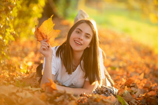 秋の黄色のカエデの葉を持つ秋の女性の屋外ポートレート秋の紅葉を持つ美しいモデルはあなたがたに落ちる