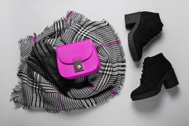 Autumn women's accessories. Fashionable female scarf, boots, pink bag, gloves on gray background. Top view. Flat lay