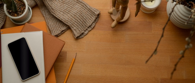 Foto area di lavoro autunnale con copia spazio, smartphone, quaderni, maglione e decorazioni sul tavolo di legno