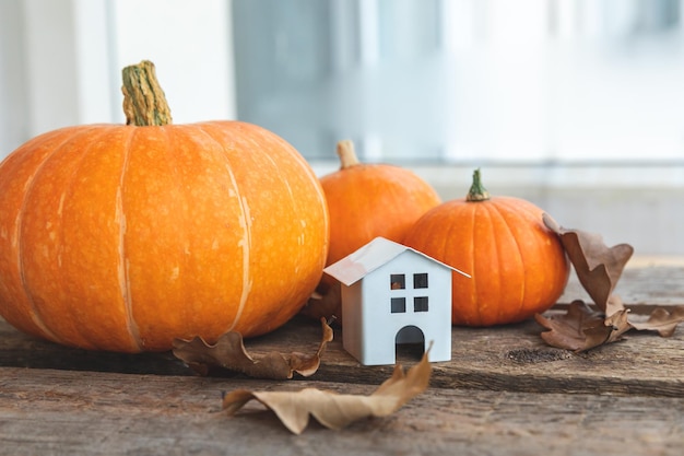 Sfondo autunnale casa giocattolo e zucca su sfondo di legno banner di ringraziamento copia spazio hygge