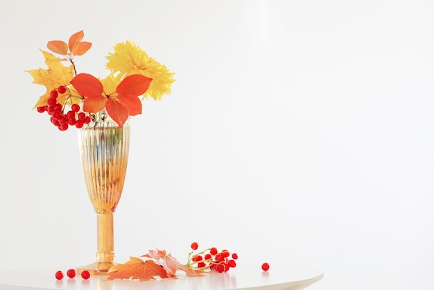 白い背景の上のガラスの花瓶の秋の花束
