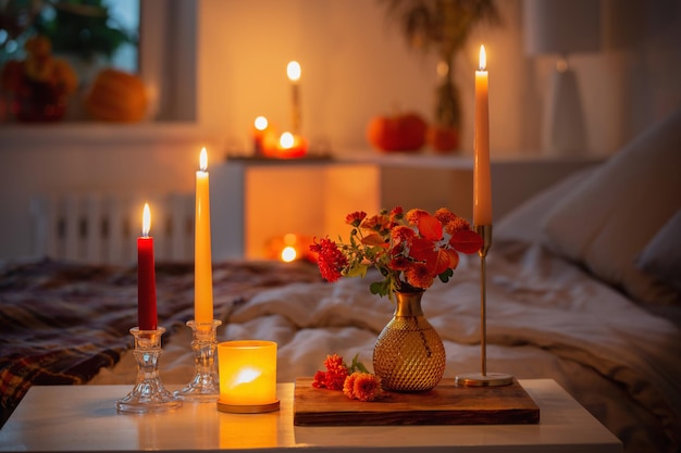 autumnal chrysanthemum in vase with burning candles in bedroom