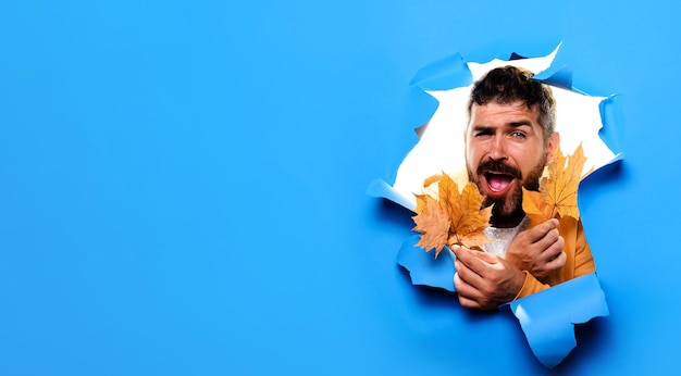 Photo autumnal mood happy bearded man in autumn wear with fall leaves looking through paper hole autumn