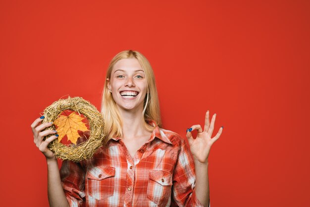 Autumnal mood happy girl with autumn wreath shows ok sign copy space for advertise autumn fashion