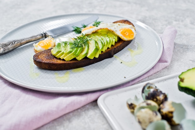 Avacado sandwich with egg on toast of black bread. 