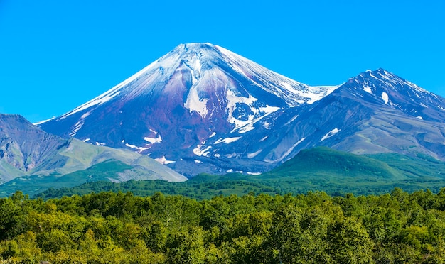 雪に覆われた頂上を持つ秋のカムチャツカのアヴァチンスキー火山