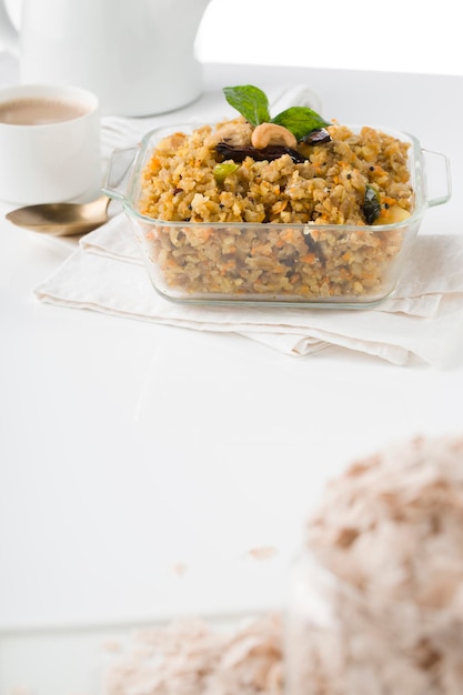 Aval upma 또는 poha upma 또는 kanda poha upma, 매우 맛있고 요리하기 쉬운 건강한 인도식 아침 식사 항목이며 흰색 질감의 배경이 있는 나무 그릇에 배열되어 있습니다.