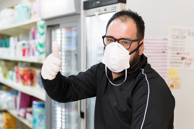 Avetrana, Italy, - Marth 16, 2020. Salesman wearing medical mask and gloves is showing that everything will be ok