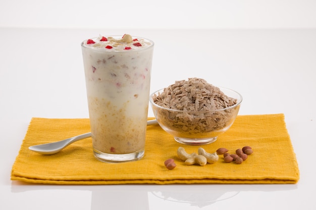 Avil milk, malabar special shake which is  arranged in a dessert glass with rice flakes and nuts placed besides it , on a yellow napkin.