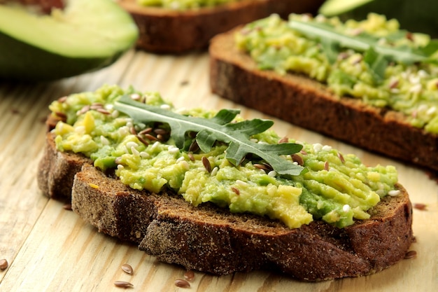 Avocado and arugula sandwiches closeup on natural wooden table.