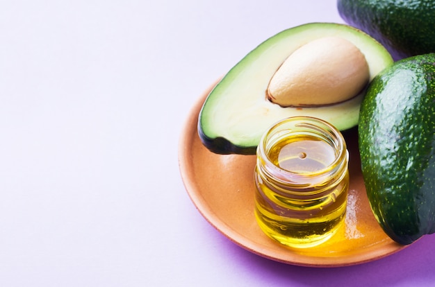 Avocado and avocado oil on pink background with copy space.