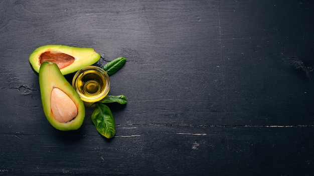 Avocado and avocado oil on a wooden background Top view Free space for your text