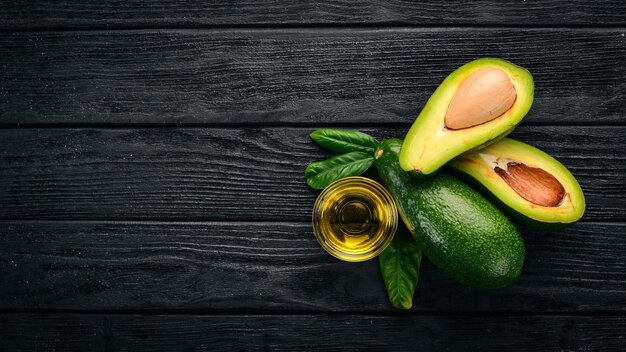 Avocado and avocado oil on a wooden background Top view Free space for your text