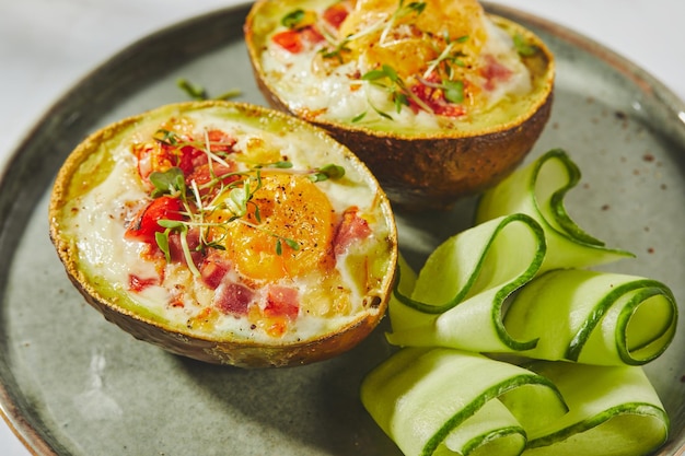 Avocado al forno con uova, prosciutto, pomodori e formaggio, ricetta del pranzo cheto dopo la cottura