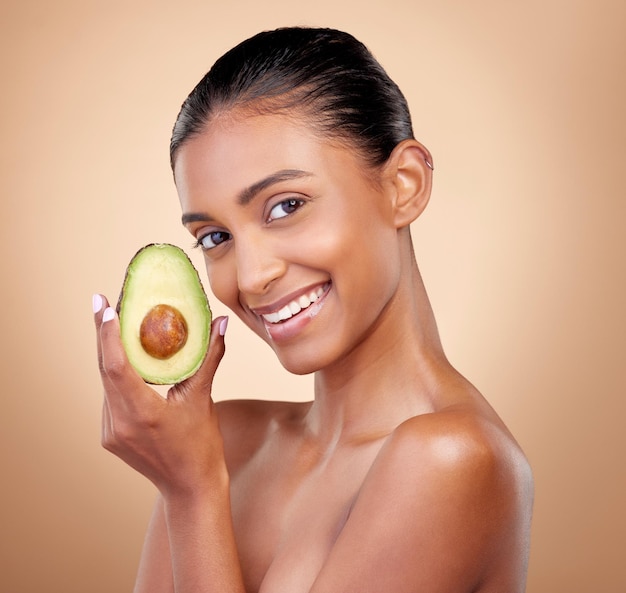 Avocado beauty and portrait of happy woman in studio background and aesthetic glow Face of indian model natural skincare and fruit for sustainable cosmetics vegan dermatology and facial benefits