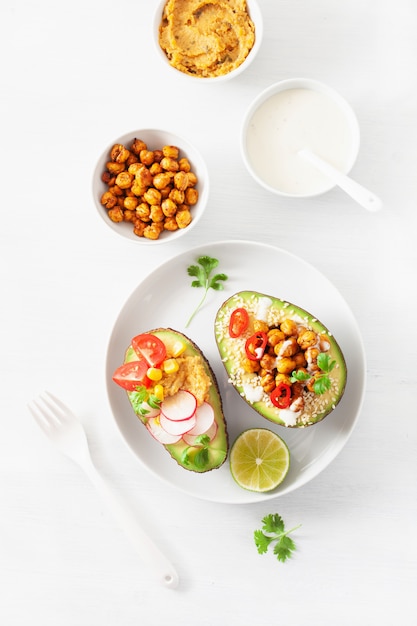 Avocado boats stuffed with hummus, tomatoes, radish, roasted chickpea