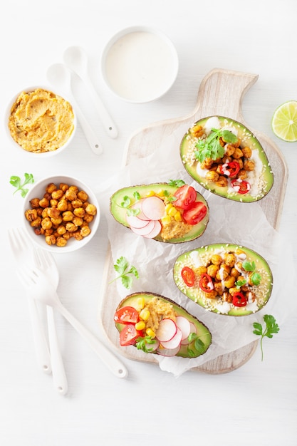 Avocado boats stuffed with hummus, tomatoes, radish, roasted chickpea