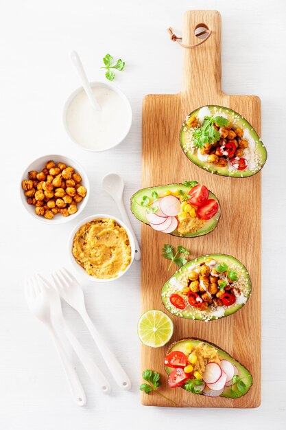 Avocado boats stuffed with hummus, tomatoes, radish, roasted chickpea