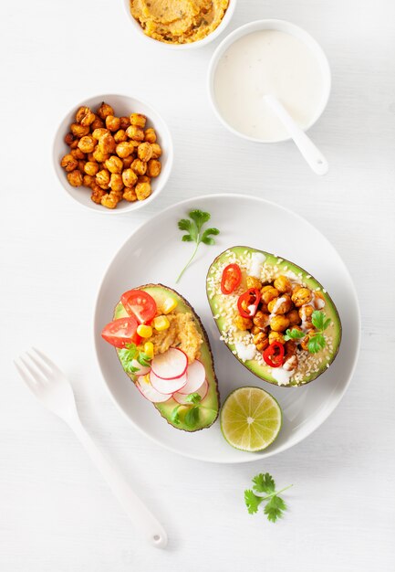 Avocado boats stuffed with hummus, tomatoes, radish, roasted chickpea