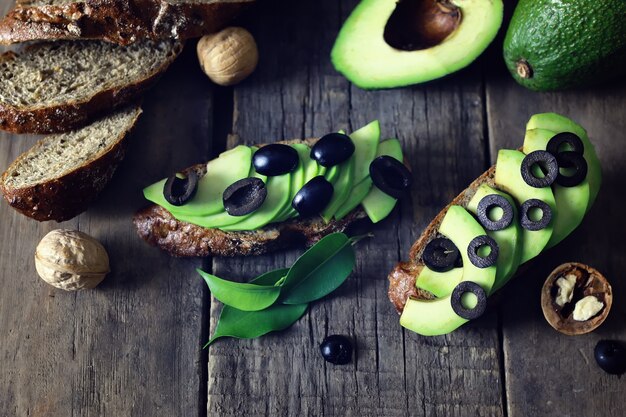 Avocado bread olives on a wooden background