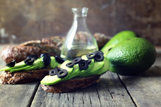 Avocado bread olives on a wooden background