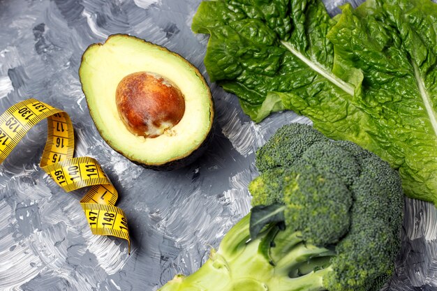 Avocado, broccoli and measure tape on gray , diet 