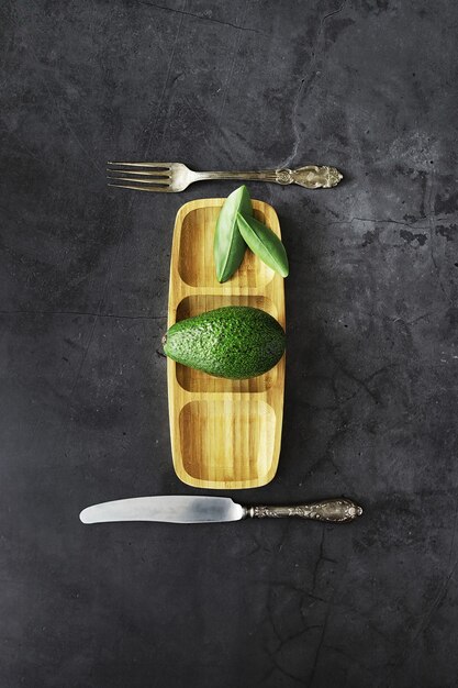 Avocado cooking recipes. Ripe green avocado on a wooden cutting board for serving.