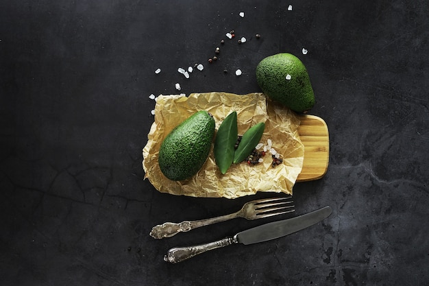 Avocado cooking recipes. Ripe green avocado on a wooden cutting board for serving.