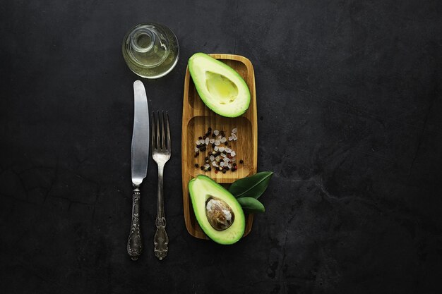 Ricette di cucina con avocado. avocado verde maturo su un tagliere di legno per servire.