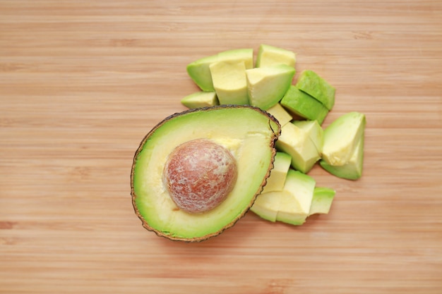 Avocado cut half and chopped on wooden board background.