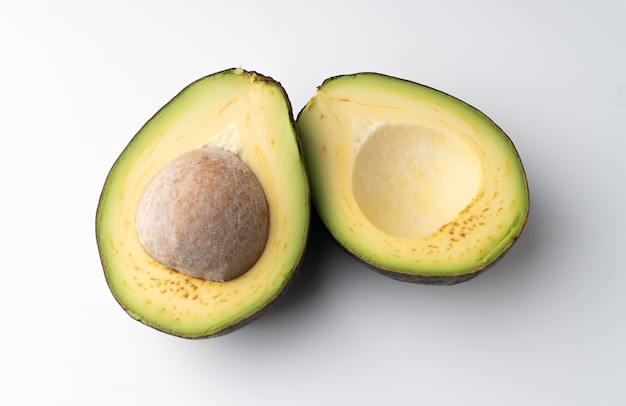 Avocado tagliato a metà isolato su uno sfondo bianco, la polpa dell'avocado è cremosa e morbida con un gusto burroso. gli avocado contengono sostanze nutritive, vitamine e grassi buoni.